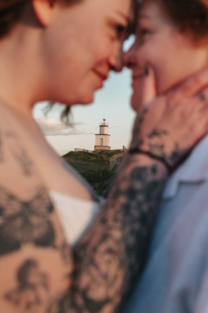 Silhouette of engaged couple embracing during golden hour in the San Juan Islands with  Cattle Point Lighthouse in the background