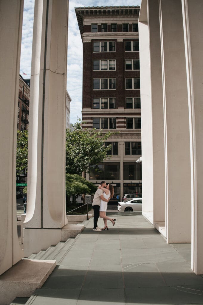 Downtown Portland engagement photo: couple kissing under a columned archway.