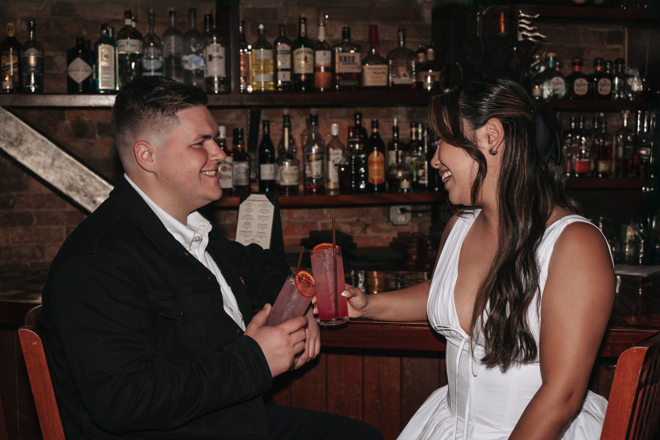 Engaged couple clinking drinks while seated at the bar at The Matador in Tacoma