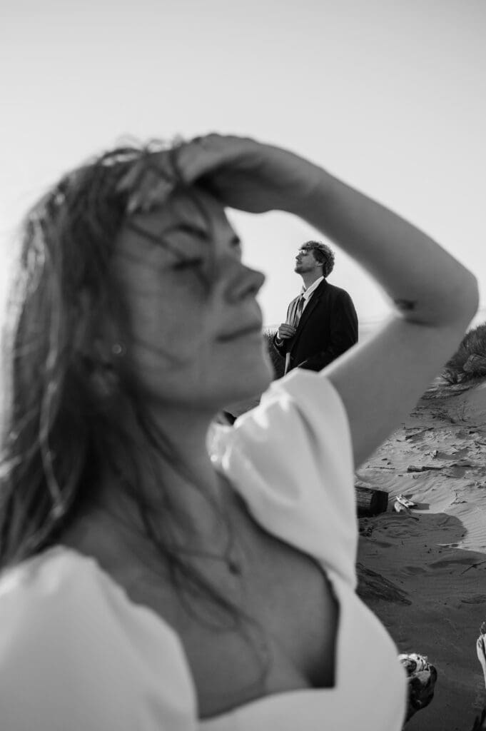 Black and white image of woman shielding her eyes as her partner stands behind her