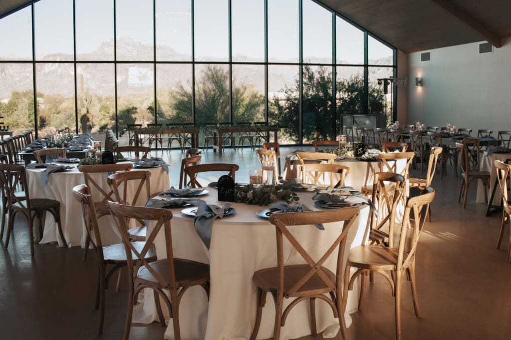 Natural light reception setup at Desert View with wooden chairs and desert view through large windows.