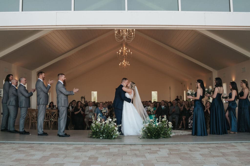 Bride and groom sharing their first kiss during wedding ceremony inside Desert View venue in Arizona.