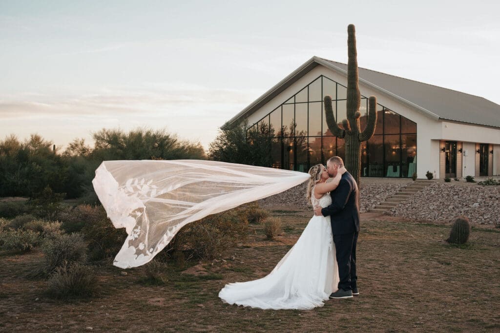 Bride and Groom share kiss in front of cactus at Desert View Weddings and Events captured by Scottsdale, AZ photographer Brayley Fleetwood.