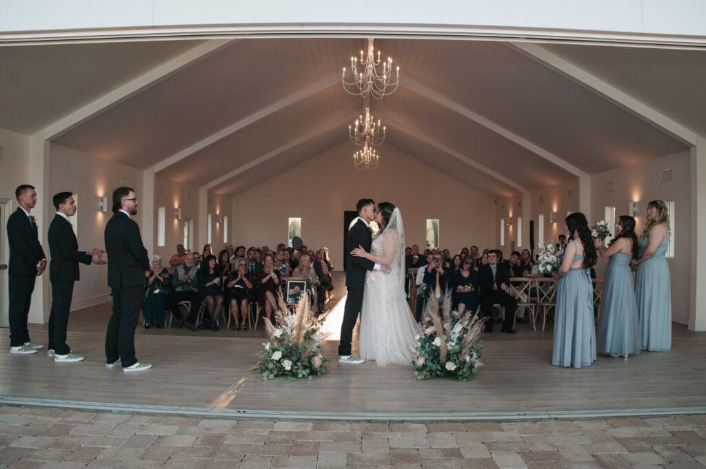 Bride and groom sharing their first kiss during wedding ceremony inside Desert View venue in Arizona.