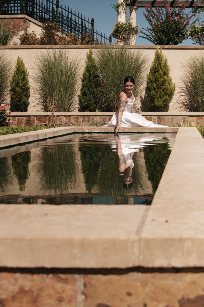 Bride sitting near reflecting pool at Chateau de Lis Portland