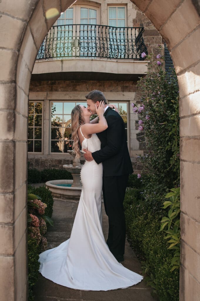 Couple kissing under stone archway at Chateau de Lis Portland