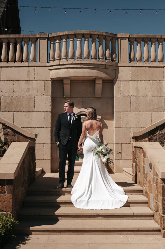Bride and groom standing in the center of a stone staircase at Chateau de Lis