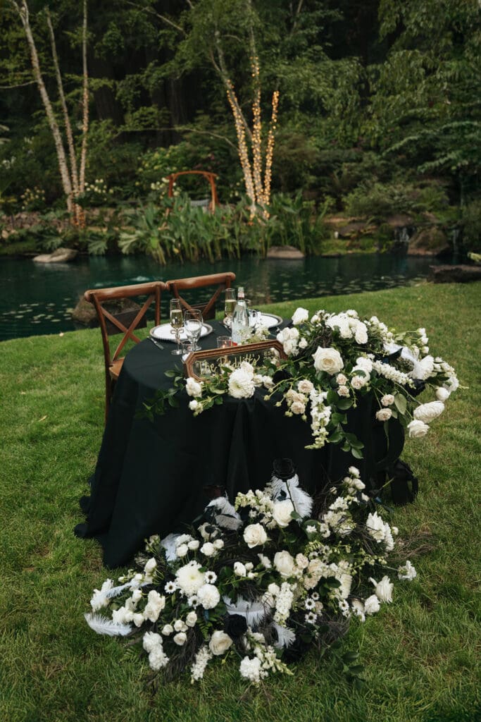 Floral-filled sweetheart table in front of the koi pond at a Nestldown wedding reception in the lawn.