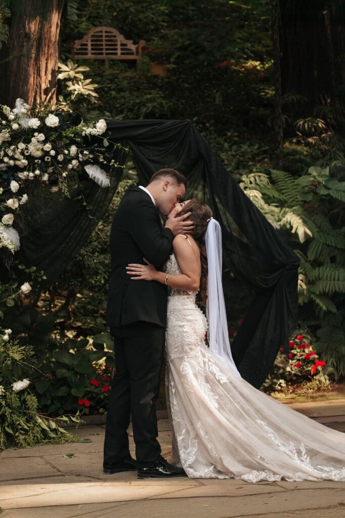 Bride and groom sharing their first kiss as a married couple surrounded by redwoods at a Nestldown wedding celebration.