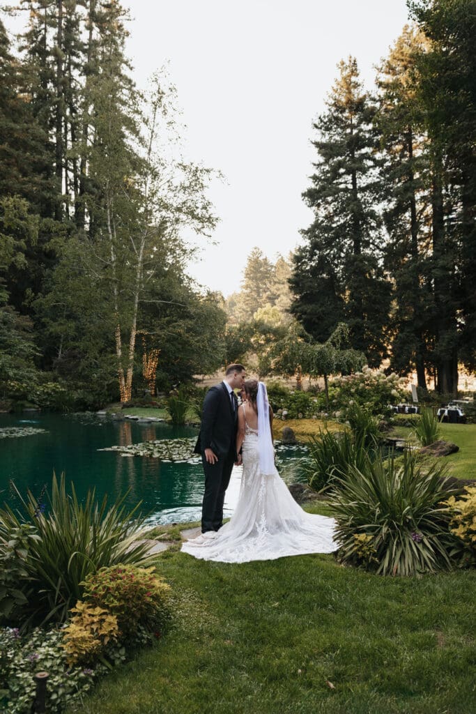 Bride and groom kissing beside the koi pond for a portrait at the romantic Nestldown in Los Gatos, California photographed by a Nestldown wedding photographer.
