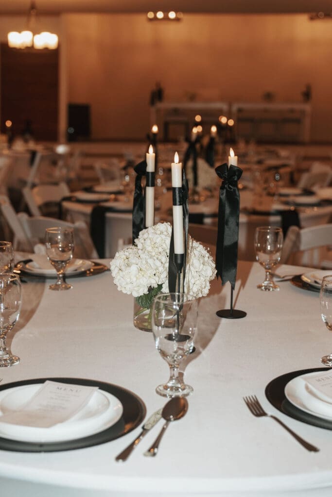 Editorial-style indoor reception table details featuring florals, glassware, and black accents.