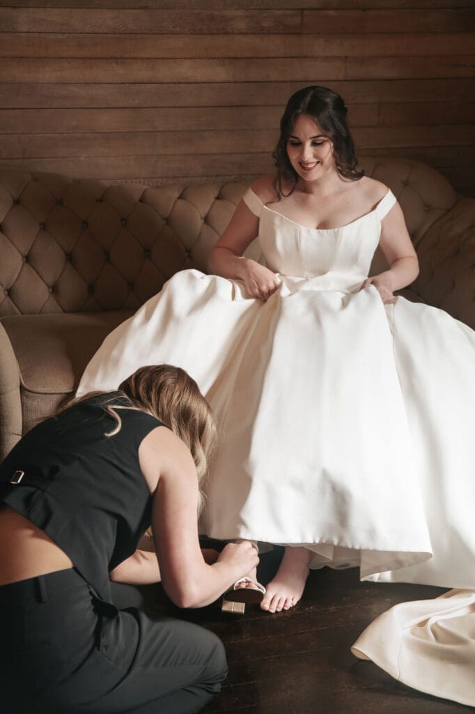 Bride's sister-in-law helps her put on shoes and get ready at Cape Horn Estate.
