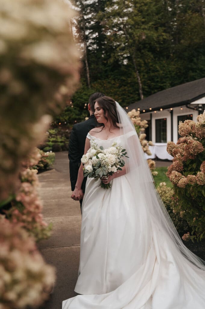 Bride and groom share a private first touch in front of the hydrangeas at Cape Horn Estate.