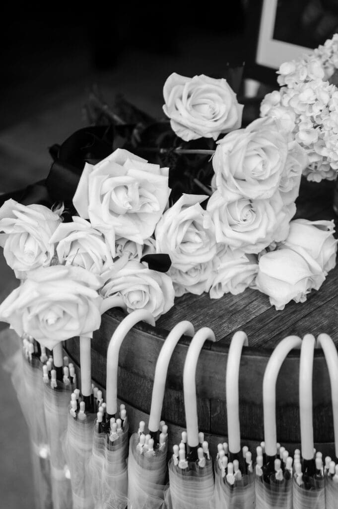 Black and white detail shot of clear umbrellas and white memorial roses.