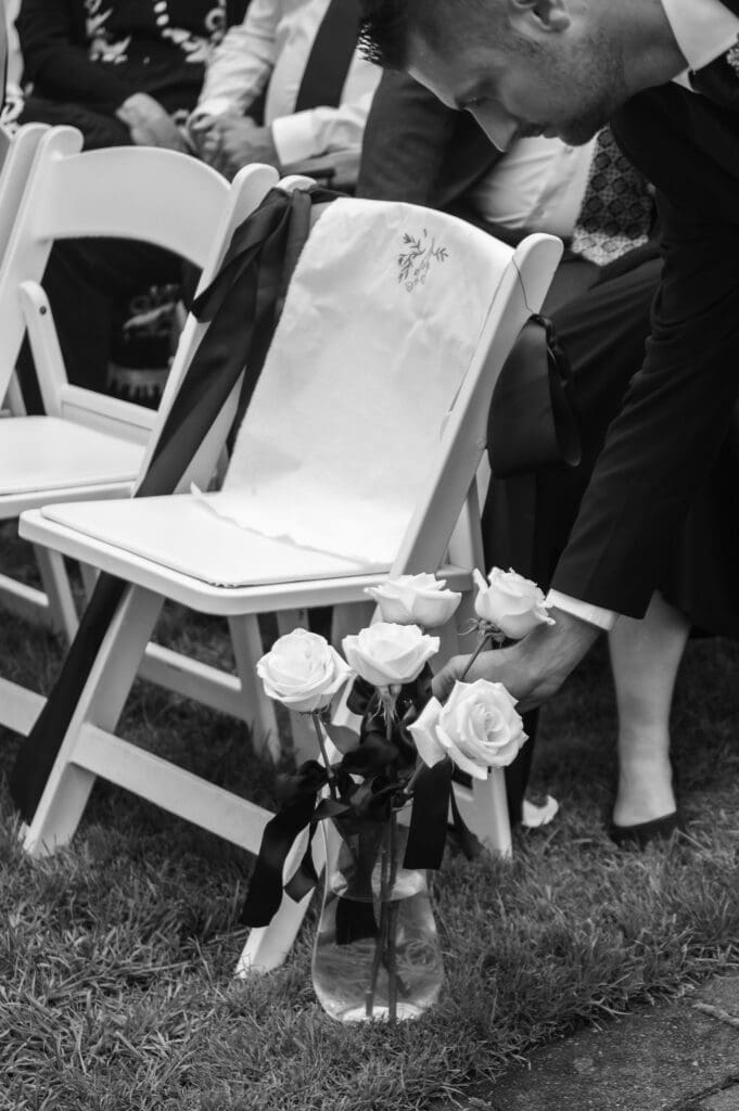 Black and white detail image of decorated memorial chair and vase with roses at Cape Horn Estate.