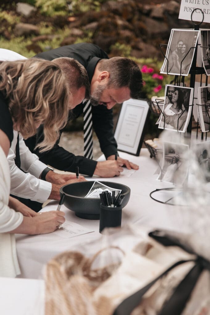 Wedding guests signing custom guest book alternative, wedding post cards, during Cape Horn Estate cocktail hour.