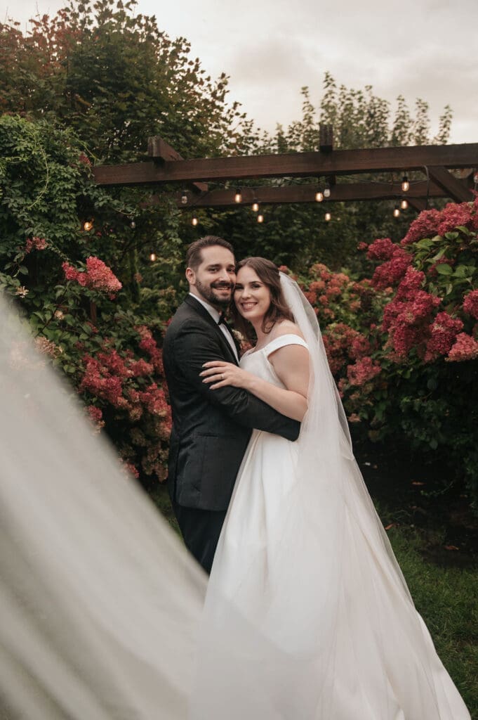 Newlyweds embracing in vibrant floral garden at Cape Horn Estate