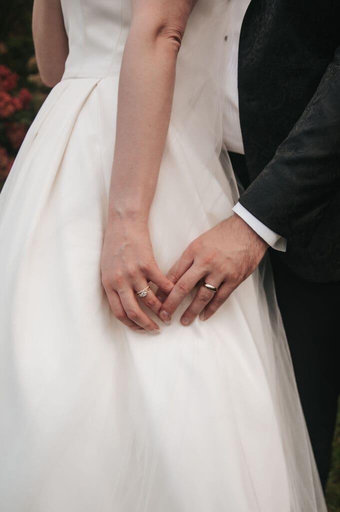 Close-up image of bride and groom holding hands showing wedding rings