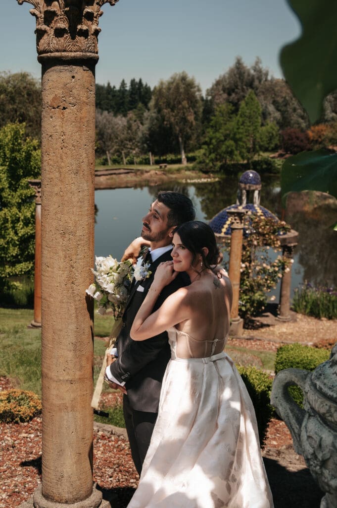 Portrait of newlyweds embracing in front of the water at Villa Catalana Cellars wedding venue near Portland.