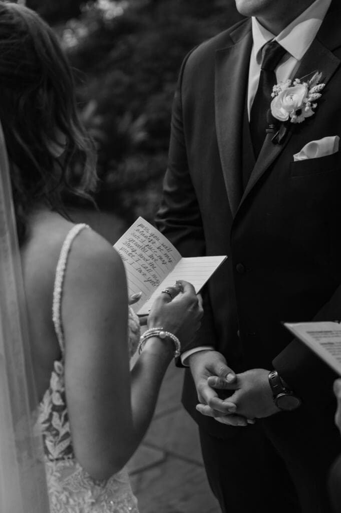 Close-up black and white photo of bride reading her vows to her groom during their wedding ceremony captured by Nestldown wedding photographer. 